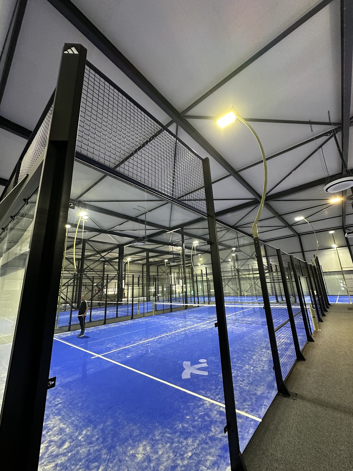Moderne indoorbanen met blauwe QuickPadel ondergrond in padel club