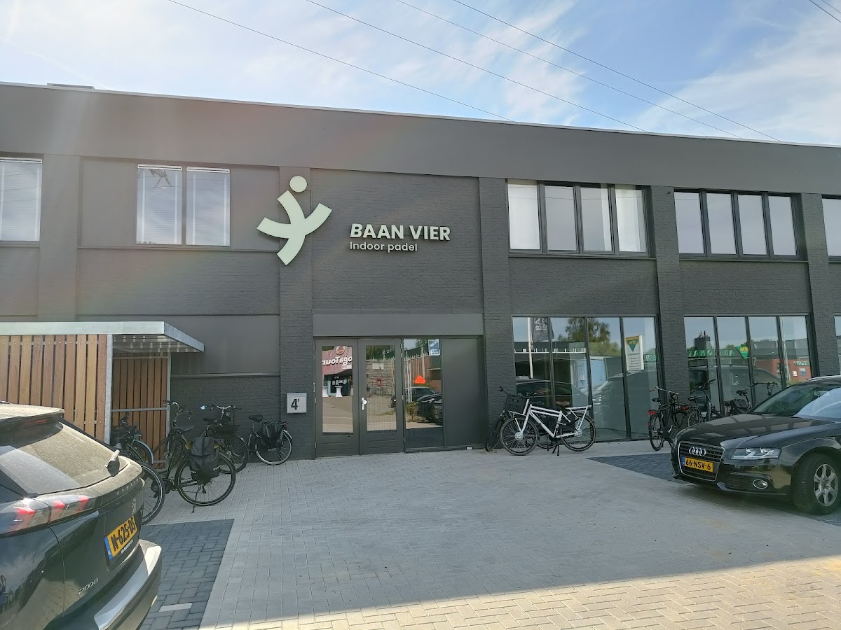 Baan Vier indoor padel clubgebouw met groene gevel en ingang met fietsen