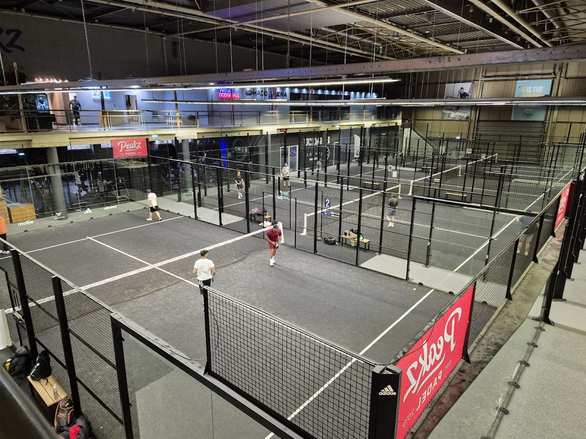 Indoorpadelbaan met meerdere courts, zwarte netting en grijze QuickPadel oppervlakken