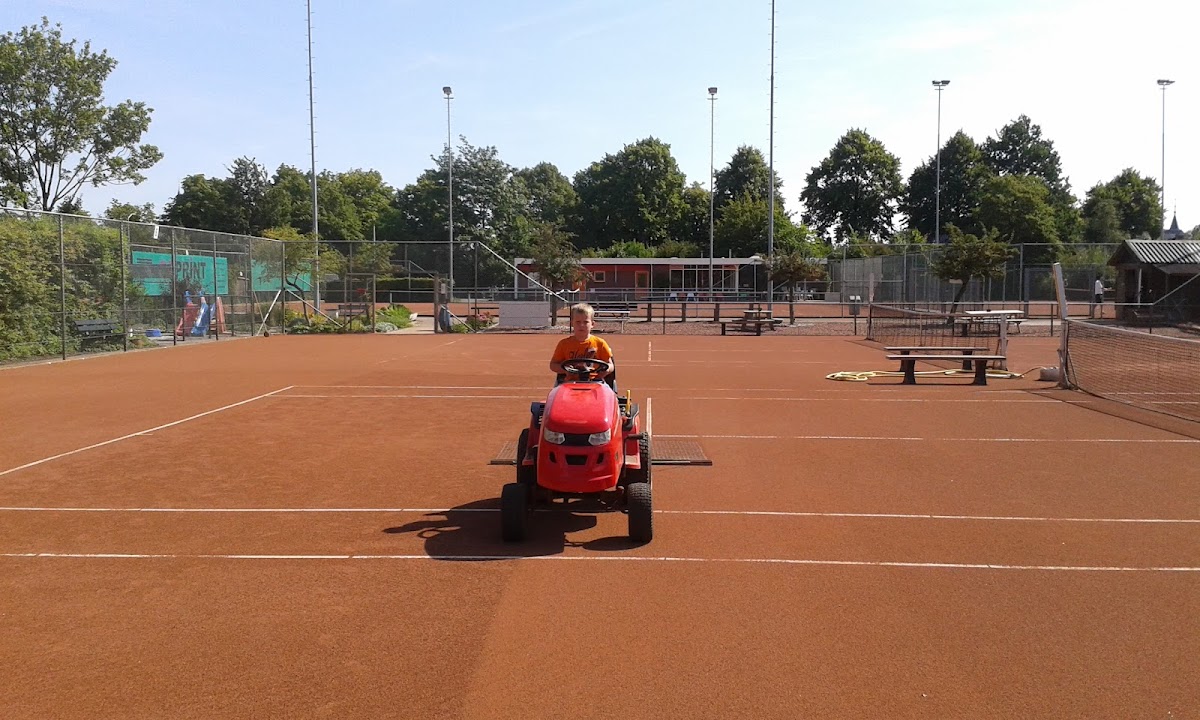 Kind op rode speeltoestel op padelbaan met oranje ondergrond