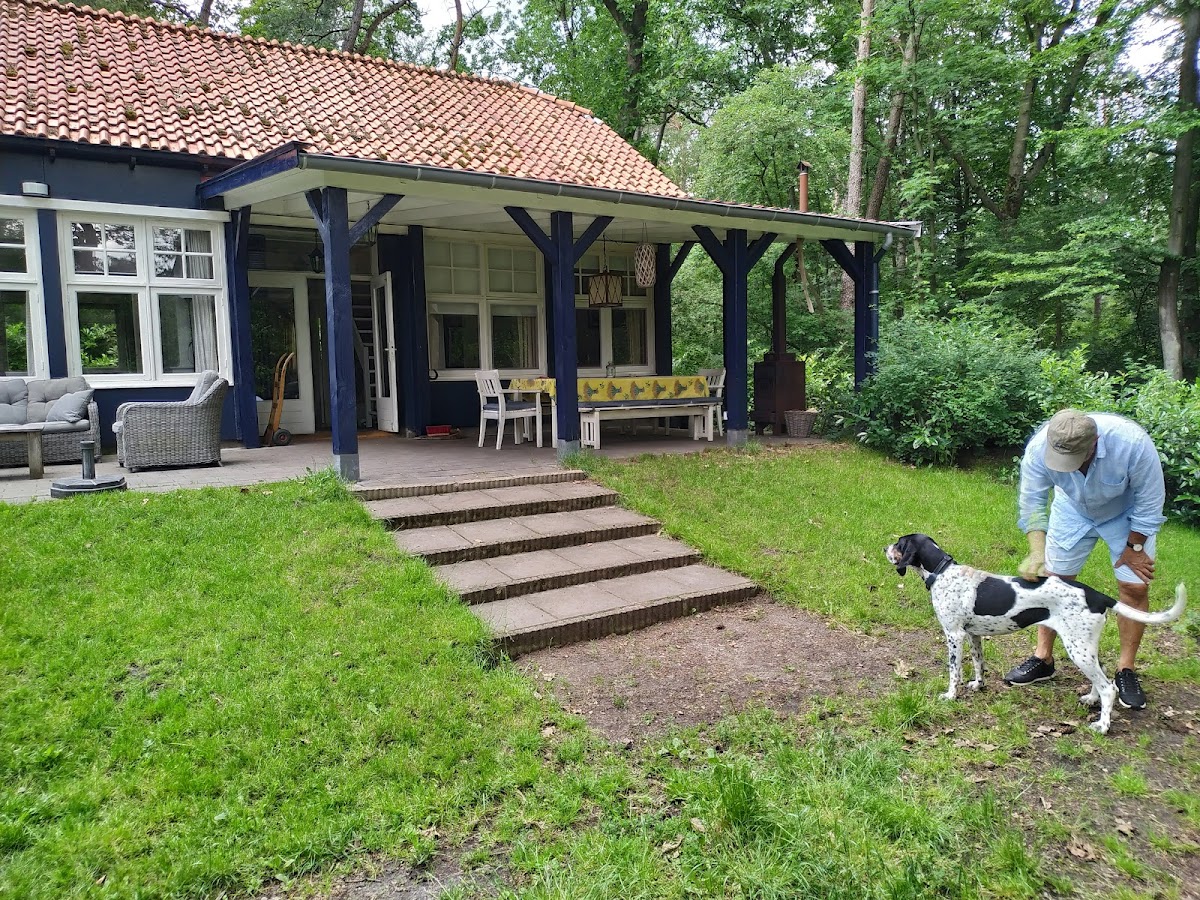 Man met hond in tuin bij moderne villa met overkapping en terras