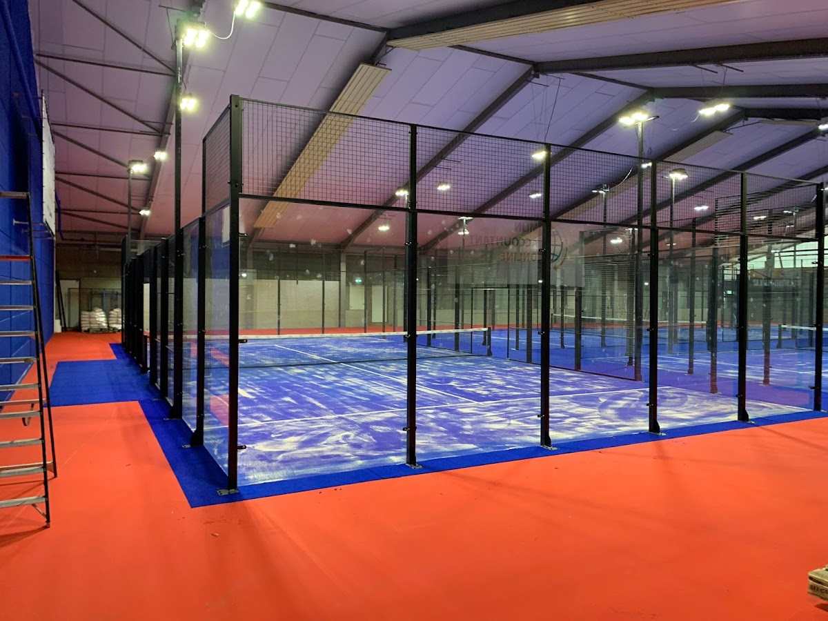 Moderne indoor padelbanen met blauwe en oranje vloer onder LED-verlichting