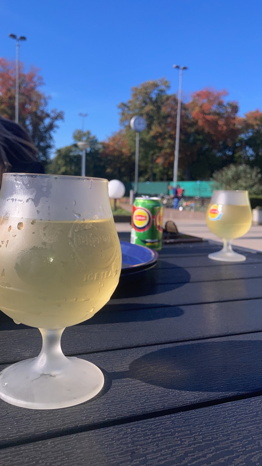 Glazen drankjes op terras met sportveld op achtergrond in herfstlicht