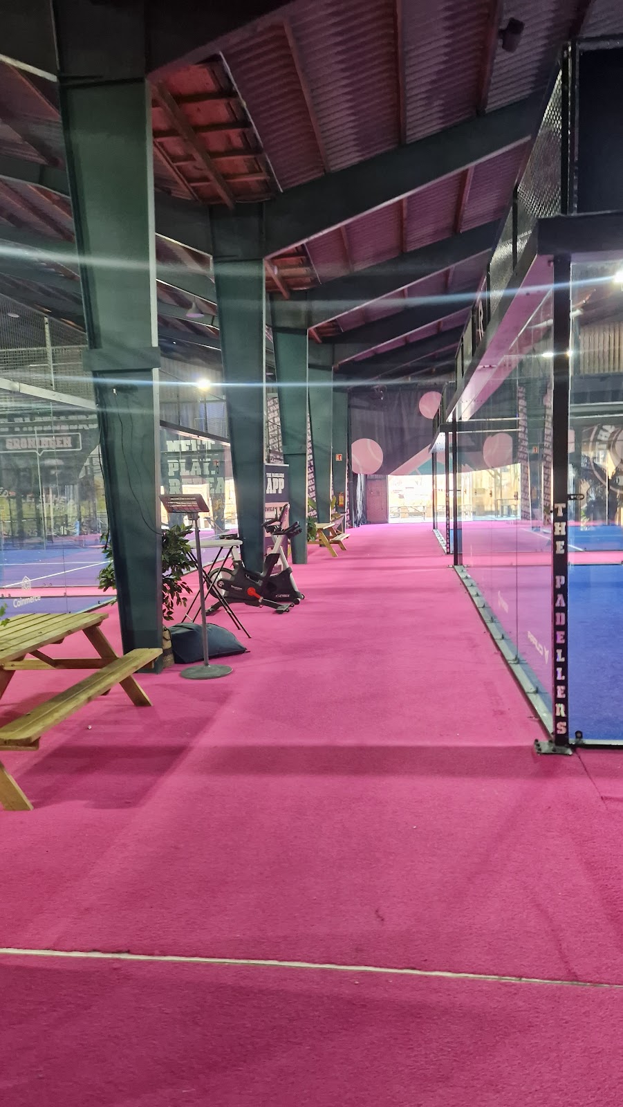 Overdekt padelclub met roze speelveld, groene zuilen en moderne voorzieningen