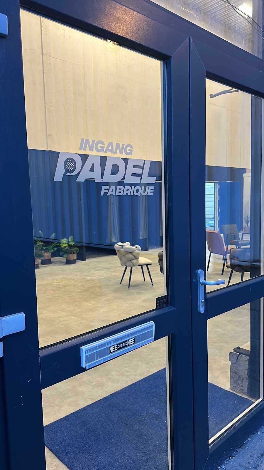 Ingang Padel Fabrique - moderne indoor padelclub met gele wanden en minimalistisch interieur