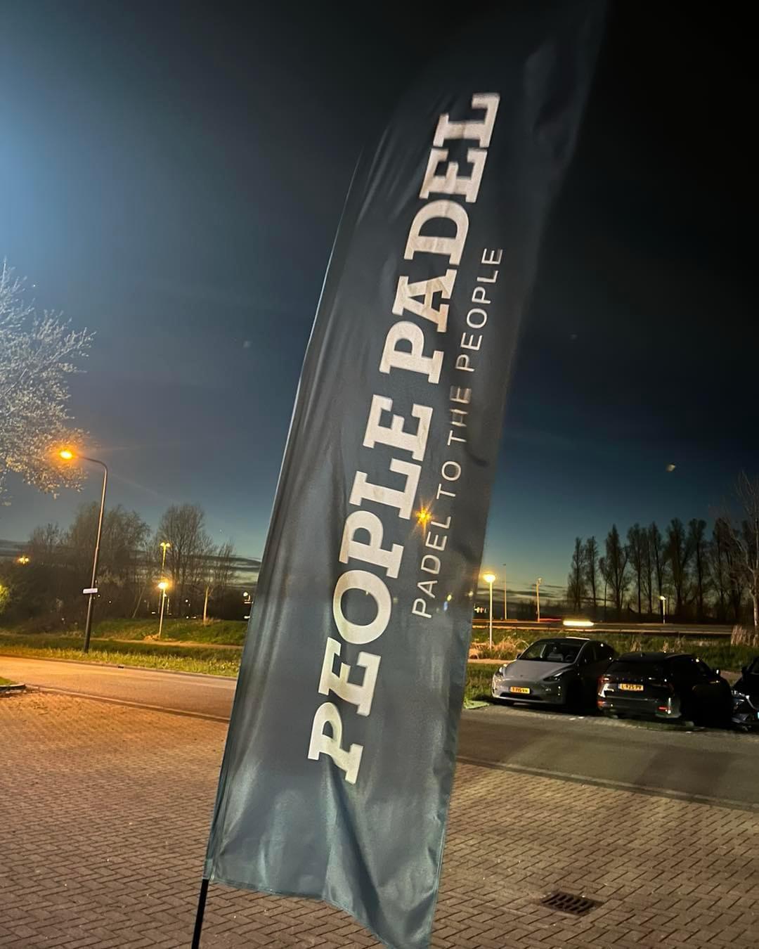 Padelclub uithangbord 'People Padel' bij avond met parkeerterrein en verlichting
