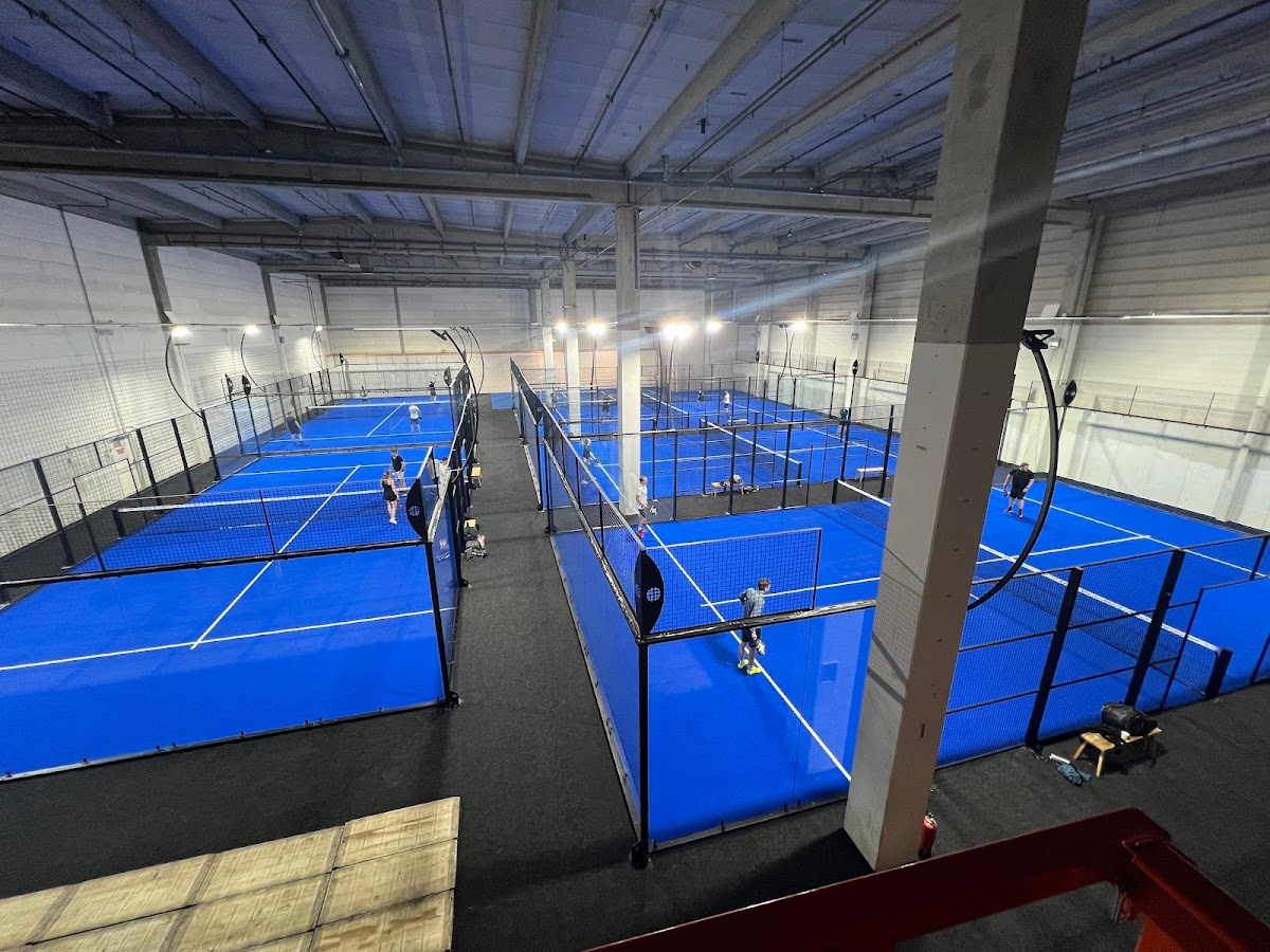 Overdekt padelclub met meerdere blauwe courts en overhead verlichting