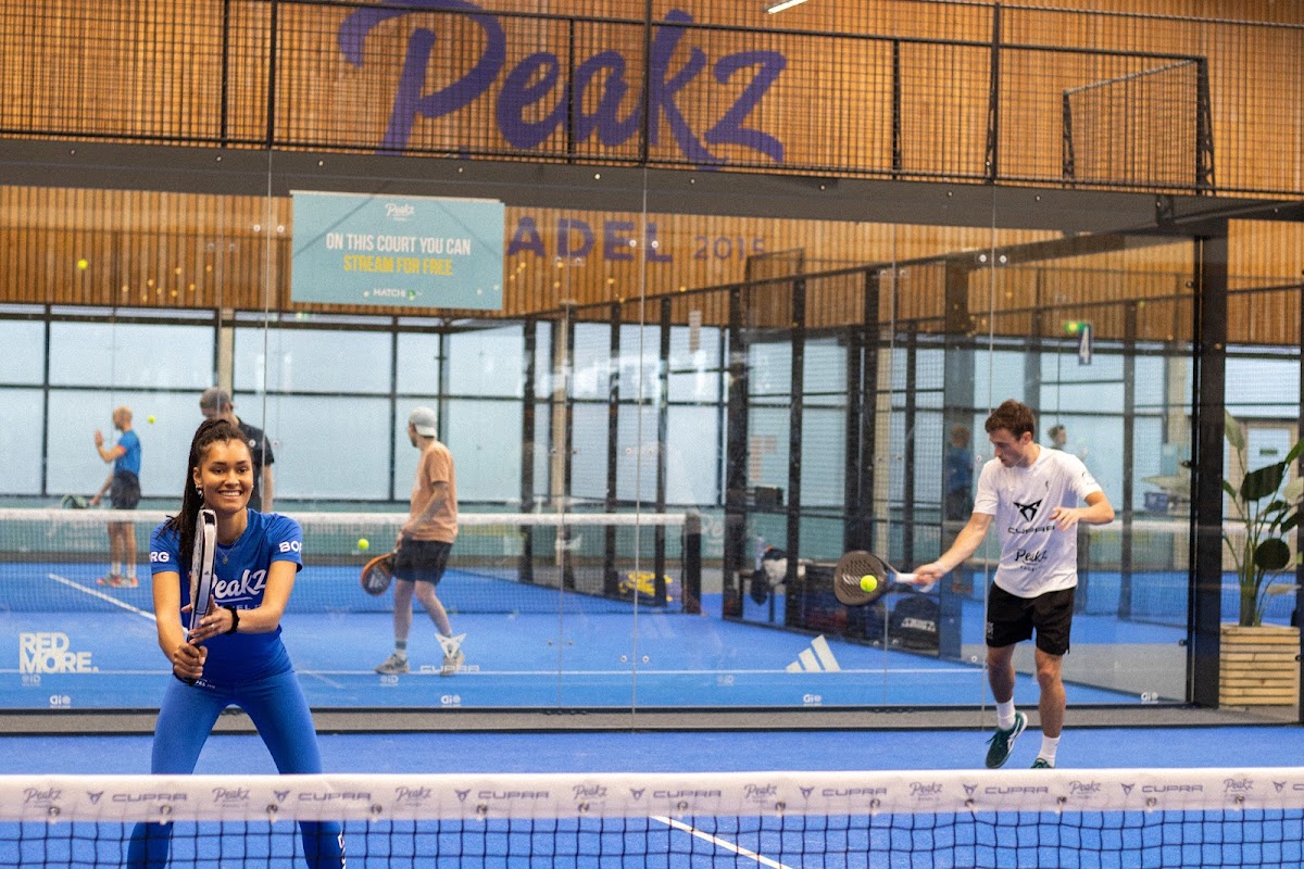 Padelbaan in Peakz clubhuis met blauwe hardcourt en twee spelers in actie