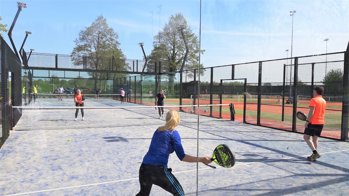 Padelbanen buiten met spelers in blauwe sportkleding op een zonnige dag