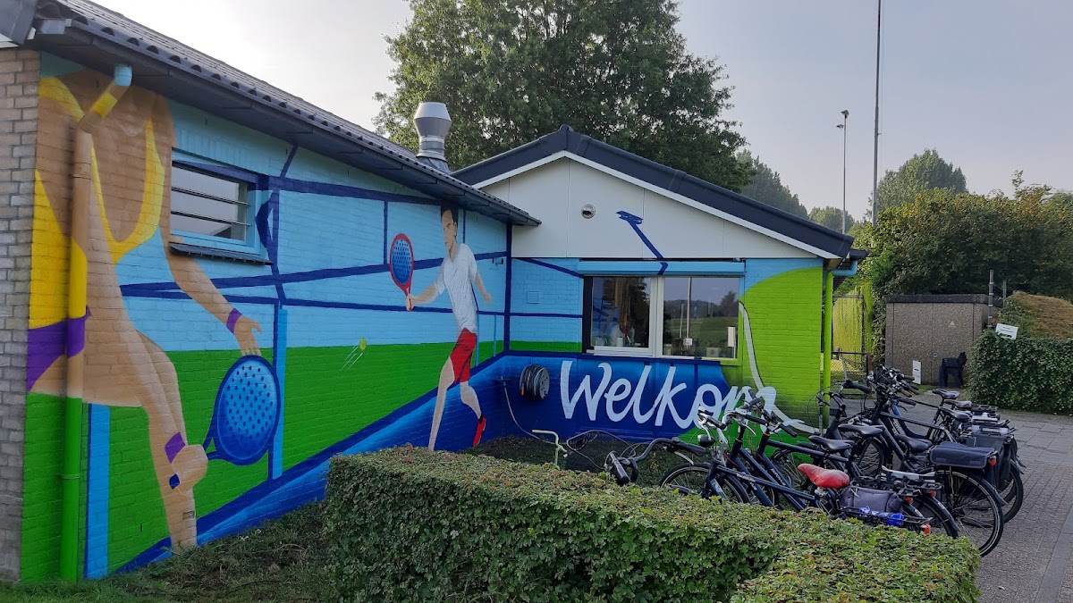 Padelbaan met kleurrijke muurschildering, fietsen geparkeerd en welkomstbord zichtbaar