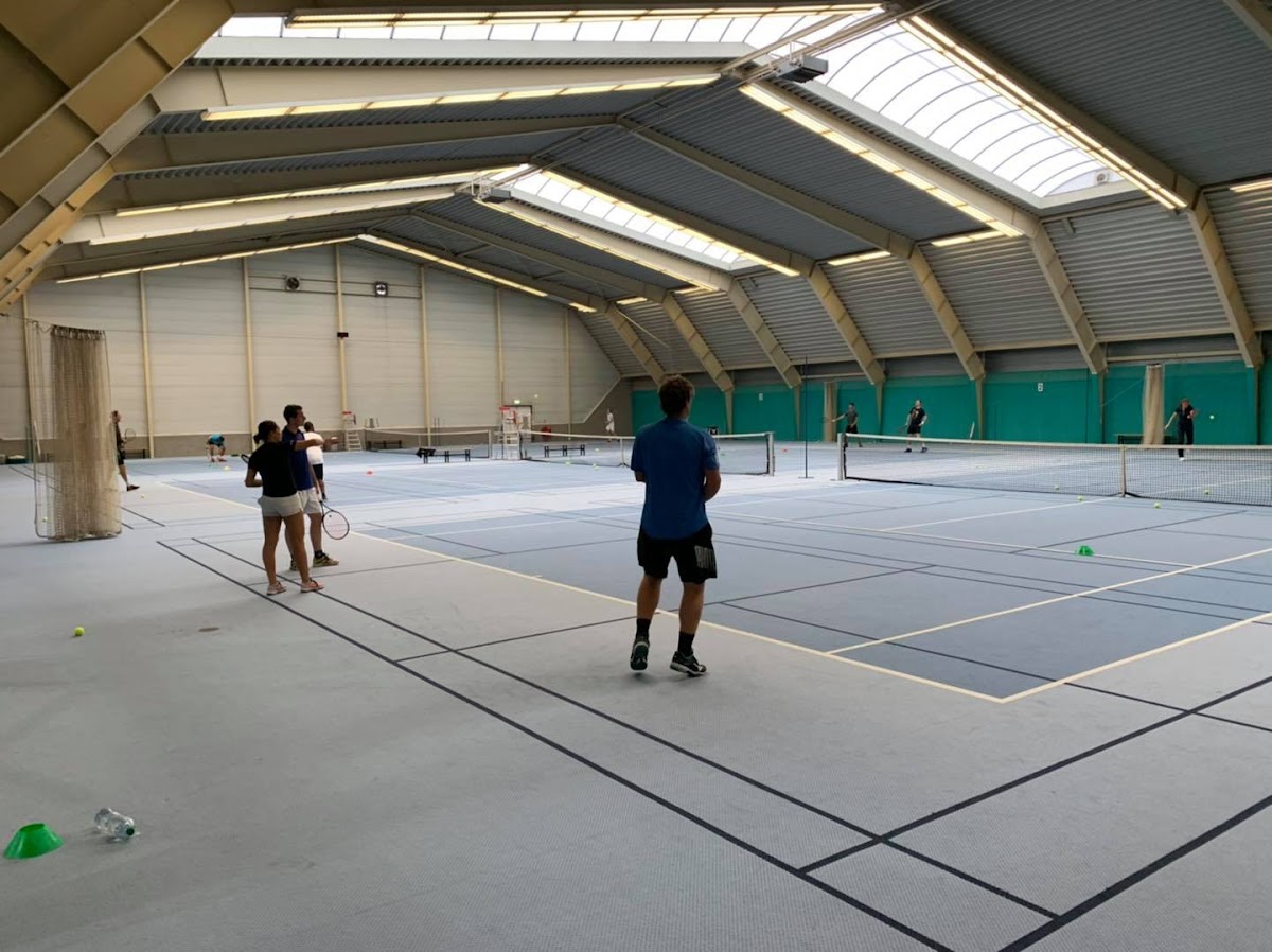 Overdekt padelbaan met meerdere courts en kunstverlichting, spelers in actie