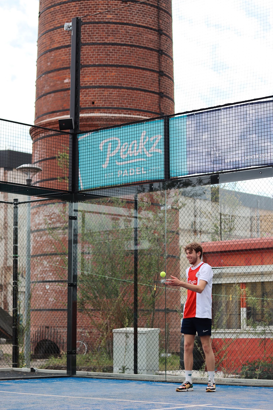 Padelspeler oefent op blauw QuickPadel-veld met bakstenindustriële achtergrond