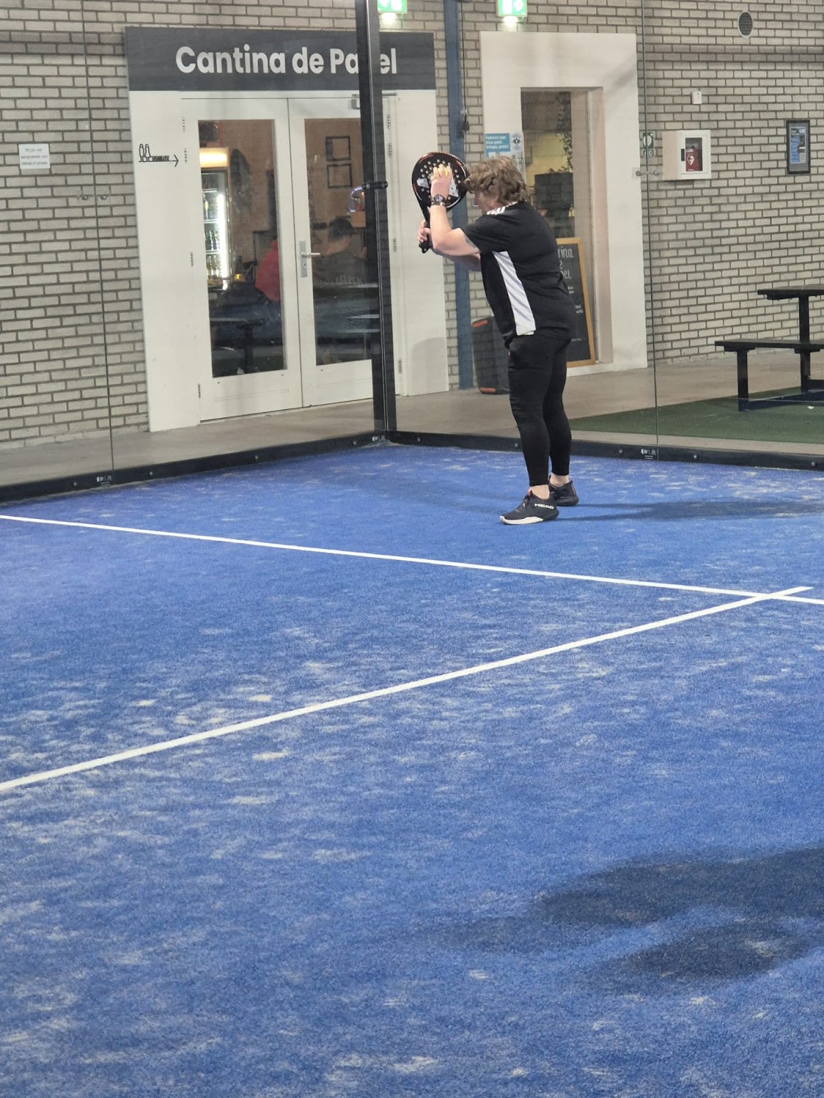 Padelspeler trainingssessie op blauwe indoor padelcourt bij Cantina de Padel