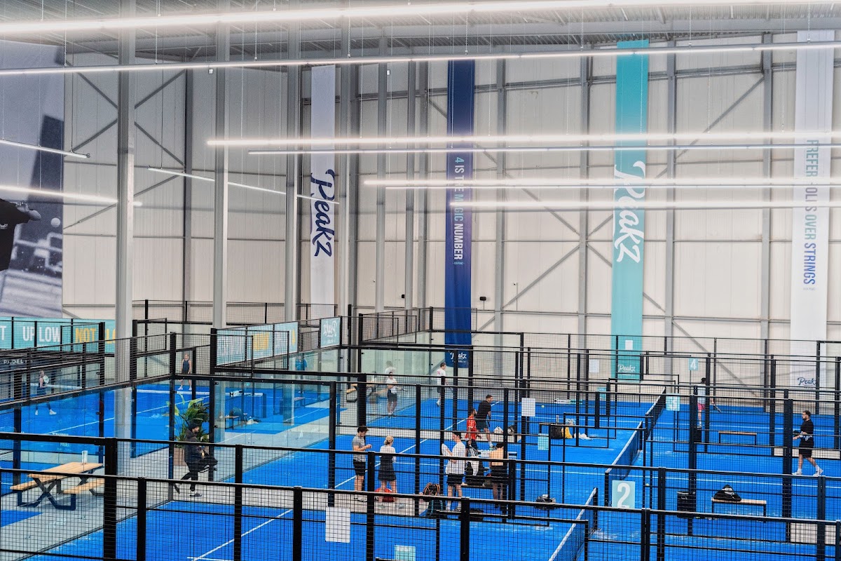 Moderne indoorbaan met blauwe QuickPadel-ondergrond en zwarte afscheiding in padelclub