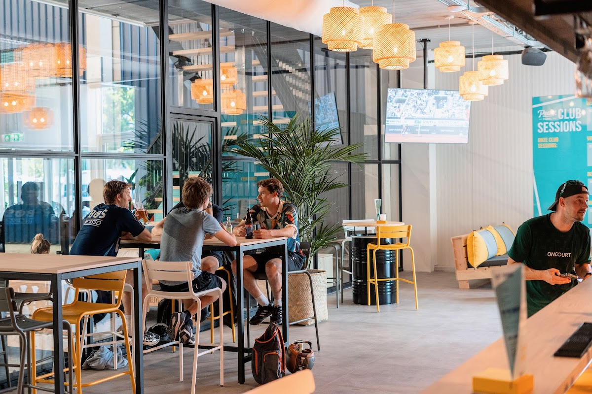 Moderne padelbaan club met zitgedeelte, hanglampen en grote ramen