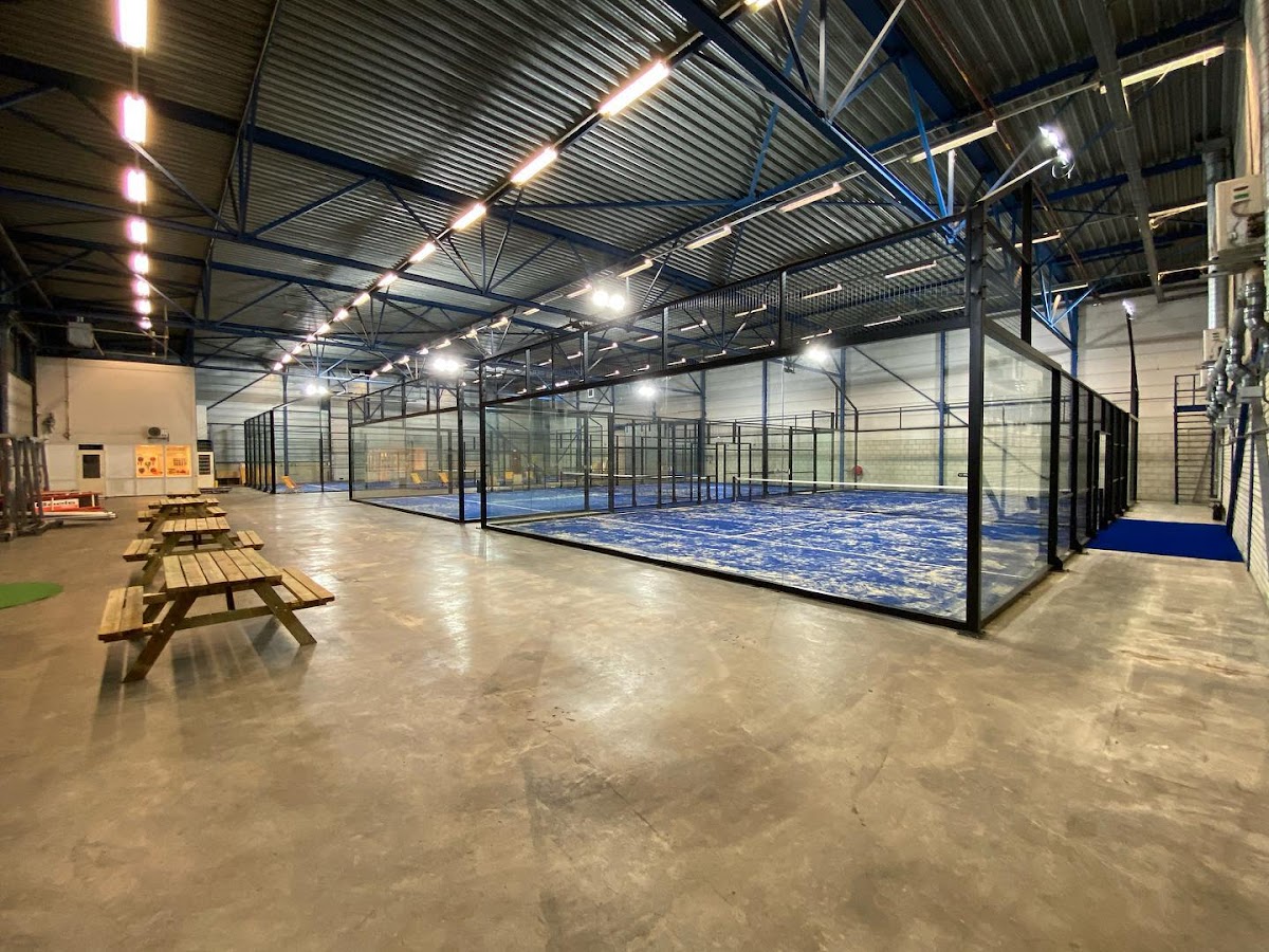 Moderne indoor padelclub met één blauwe baan, betonnen vloer en professionele LED-verlichting