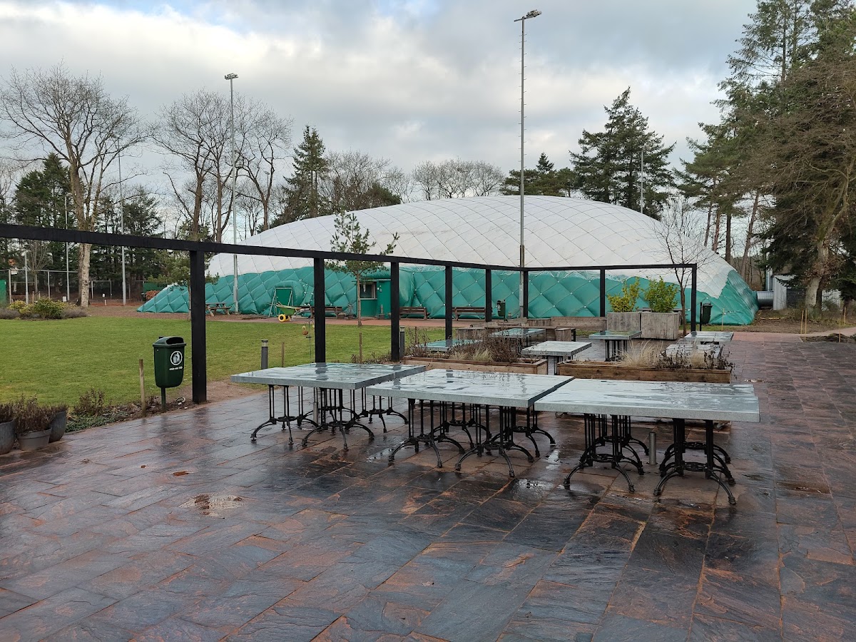 Outdoor padelclub met witte overkapping, picknickta fels en groene zijwanden