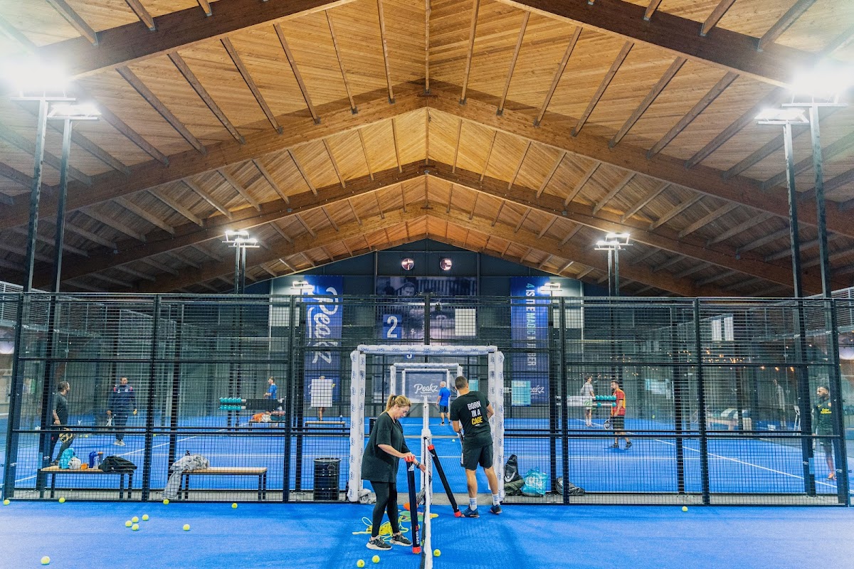 Binnenpadelclub met blauwe QuickPadel-banen, houten plafond en moderne verlichting