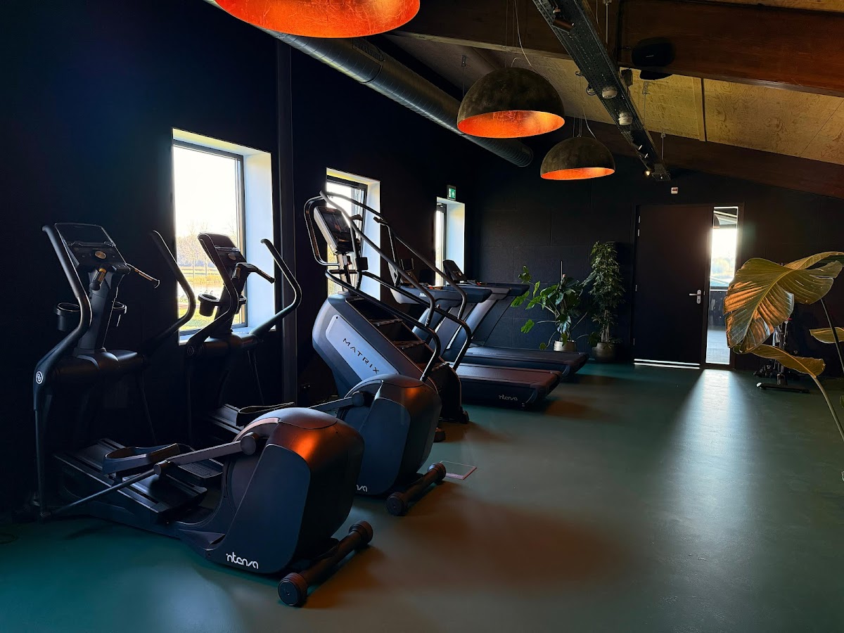 Moderne indoorfitnessstudio met Nterva hometrainers en oranje hanglampen