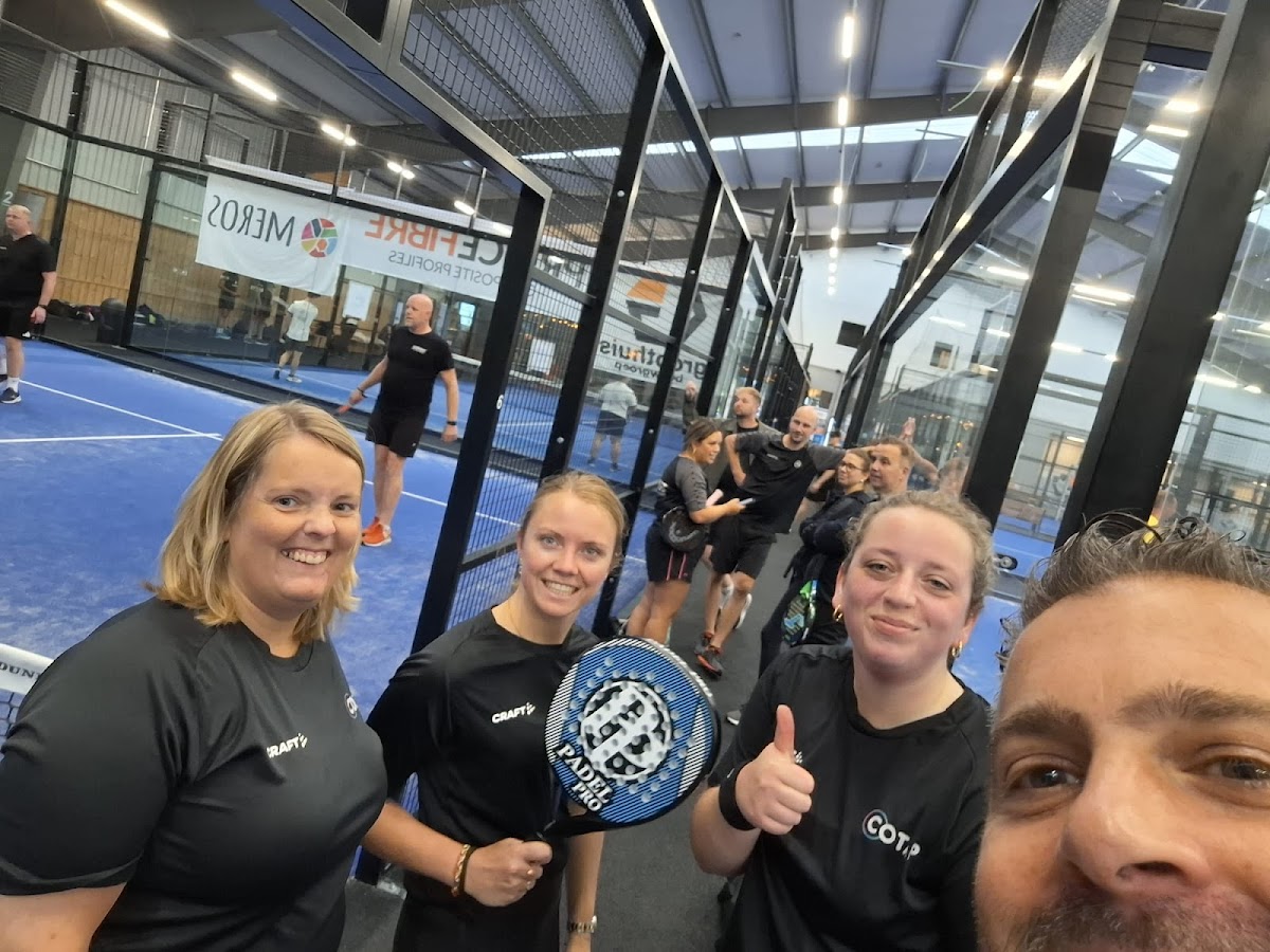 Groep spelers poseert op binnenpadelclub met blauwe QuickPadel-banen