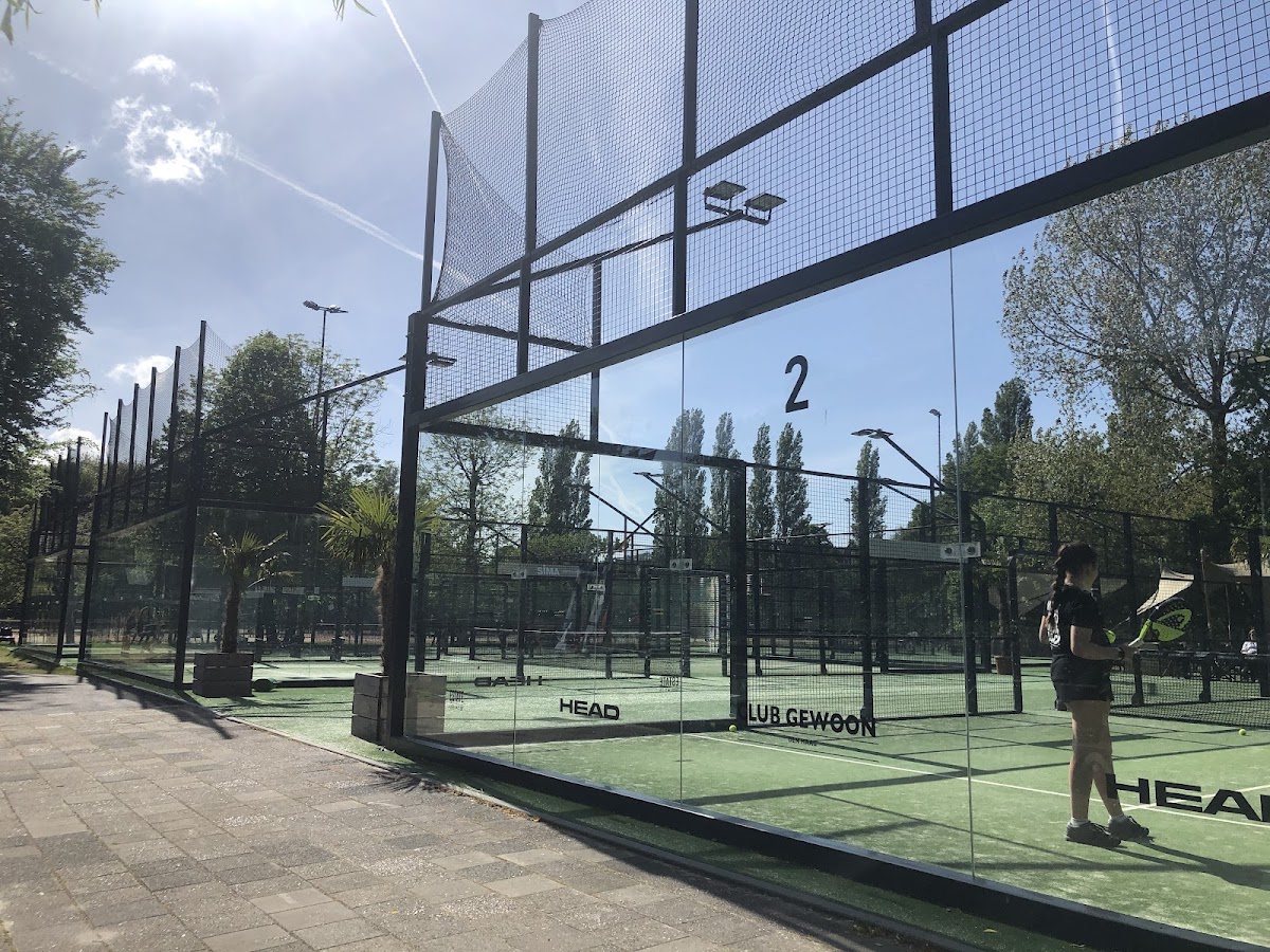 Outdoor padelbaancomplex met groene kunstgrasoppervlakken en zwarte netframes onder zonnig weer.