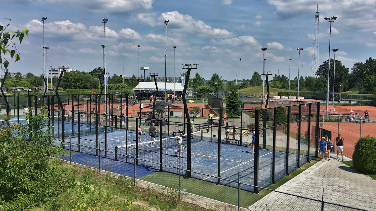 Moderne outdoor padelclub met meerdere blauwe courts, verlicht door hoge masten