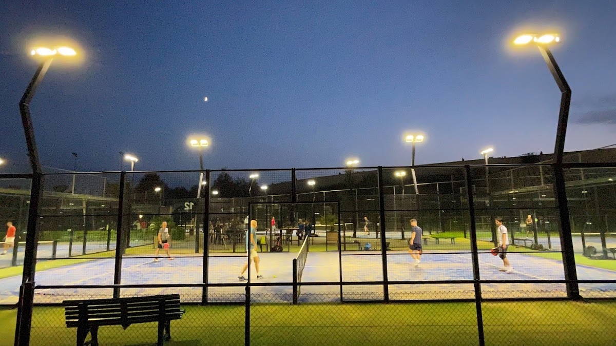 Verlichte padelbanen 's avonds met groene kunstgrasvelden en volledig gaasomheiningen