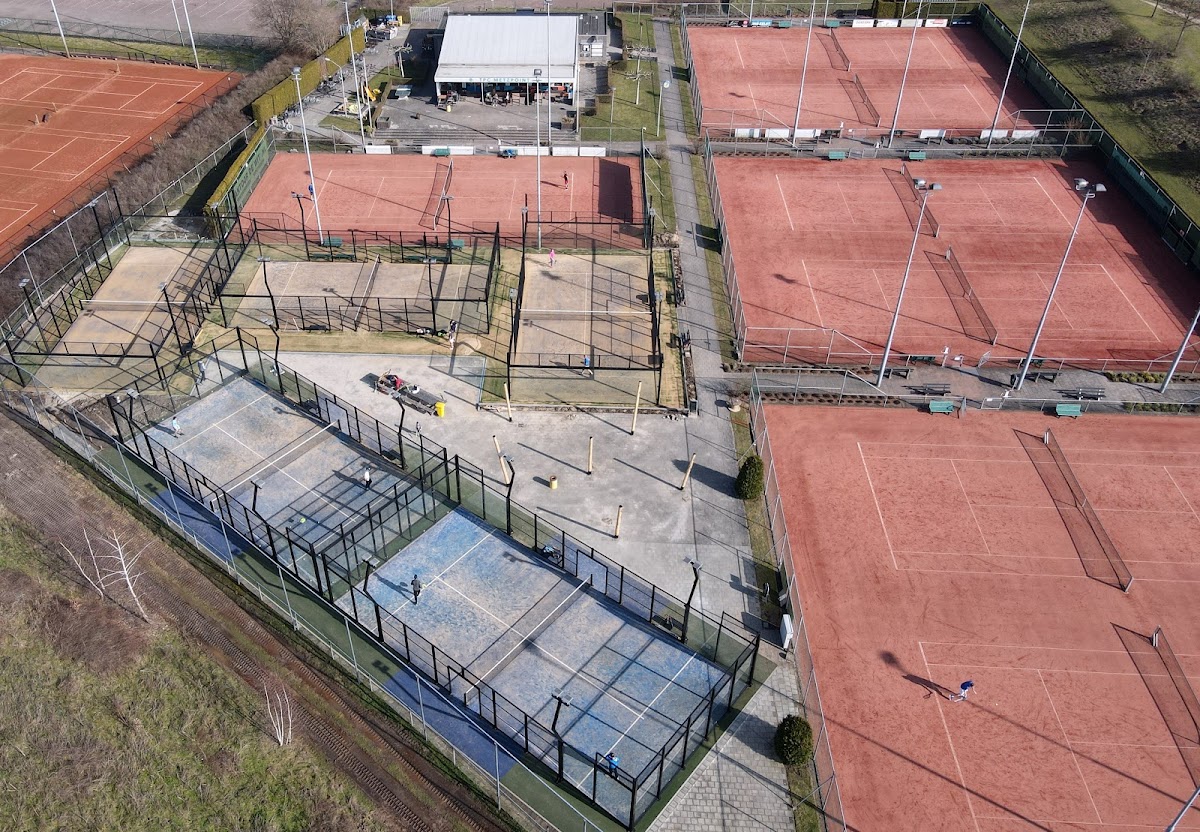 Luchtfoto padelbanen met blauwe en rode courts, centrale gebouw en groene omgeving