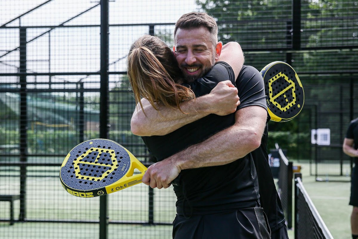 Man en vrouw spelen padel op buitenbaan met gele rackets, blijdschap en plezier