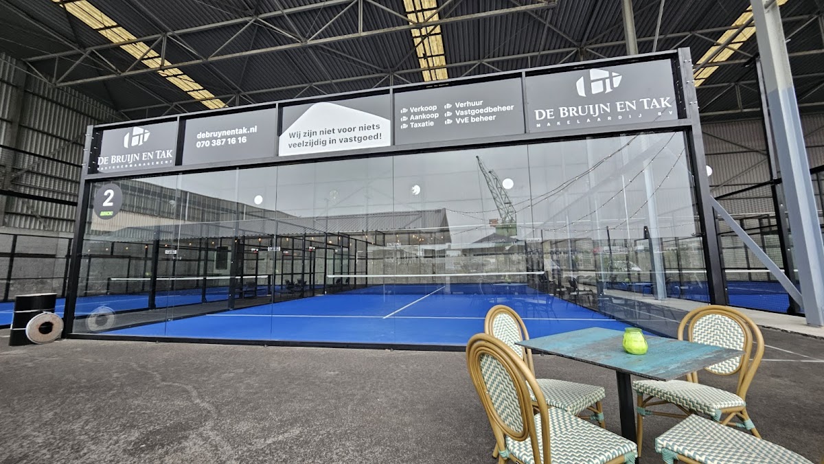 Indoorpadelbaan met blauwe QuickPadel ondergrond en glazen wanden bij De Bruijn en Tak