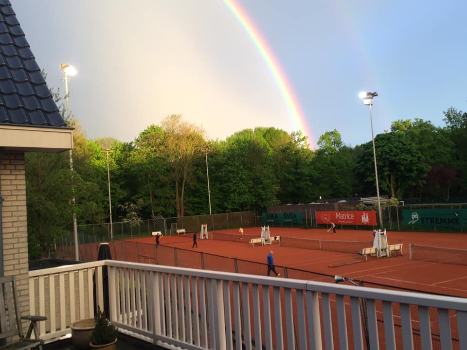 Buitenbaan padel club met rode ondergrond, regenboog en floodlights