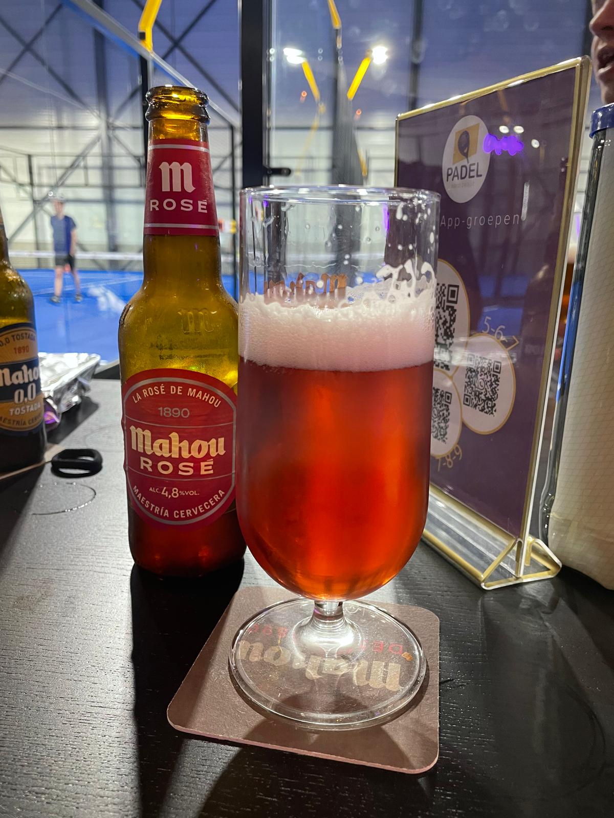 Mahou Rosé bier bij padelbaan met blauwe ondergrond en glazen wanden
