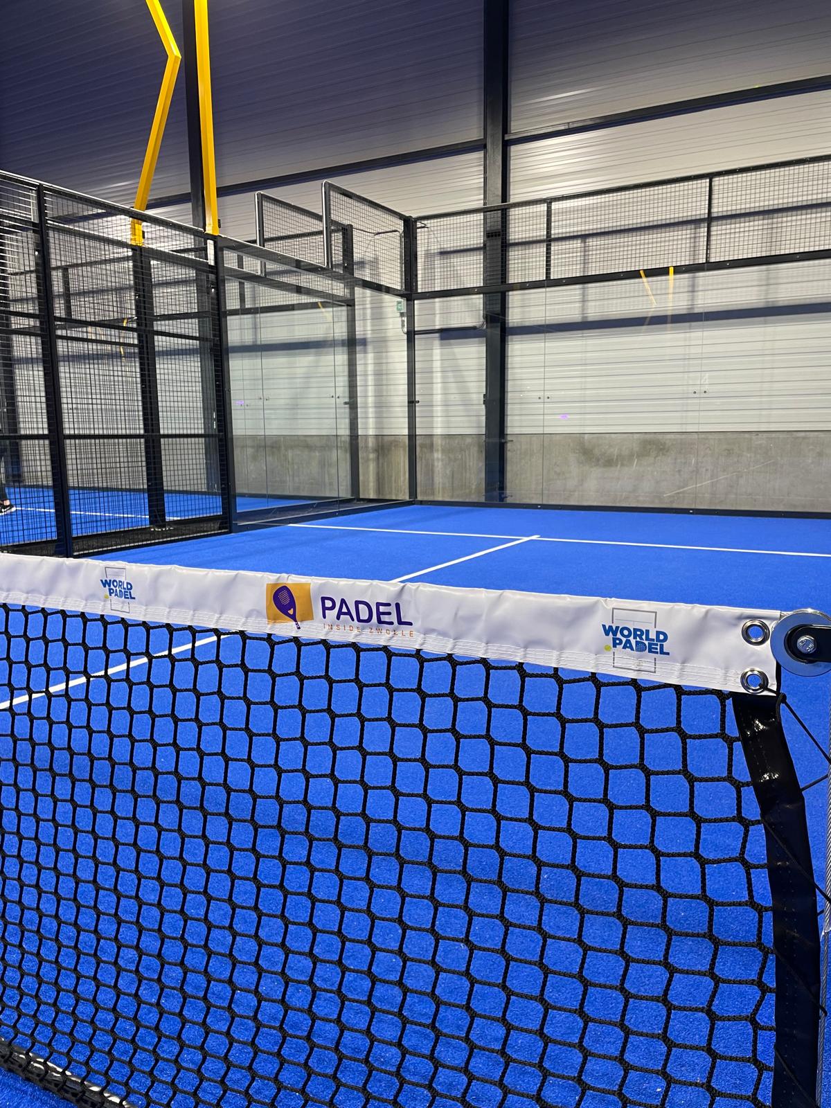 Professioneel padeltennis veld met blauw hard court en net, indoor faciliteit