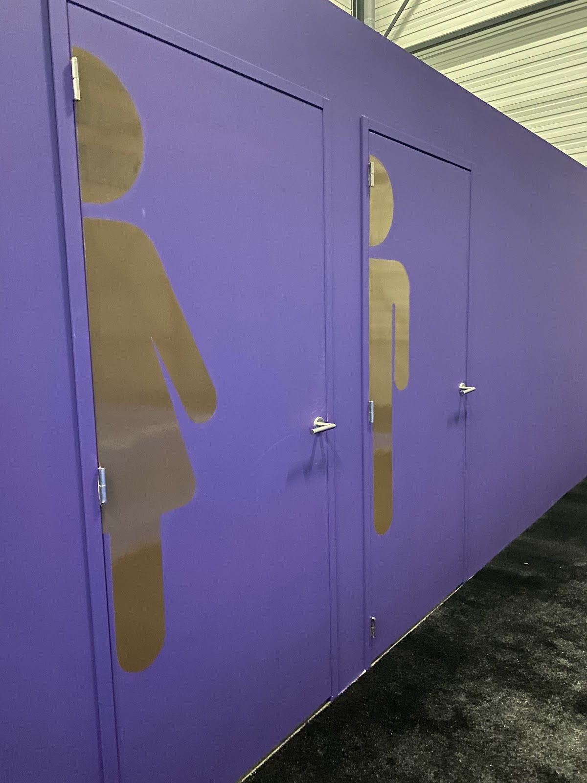 Paarse padelbanen met gele figuurmotieven op de wanden, binnenshuis.
