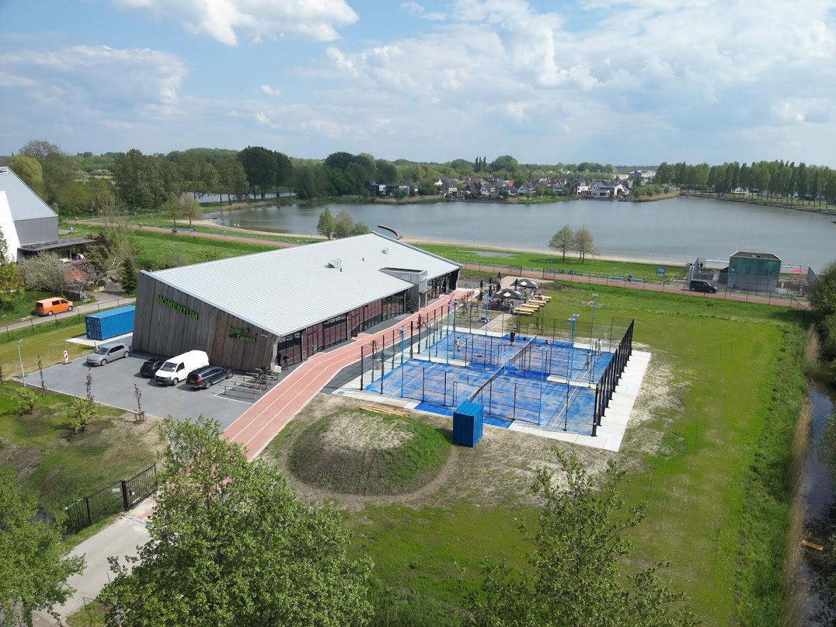 Padelclub aan het water met blauwe banen, clubhuis en groene omgeving