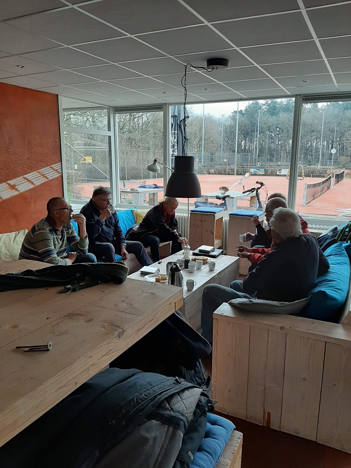 Groep mensen in padel clubhuis met uitzicht op banen