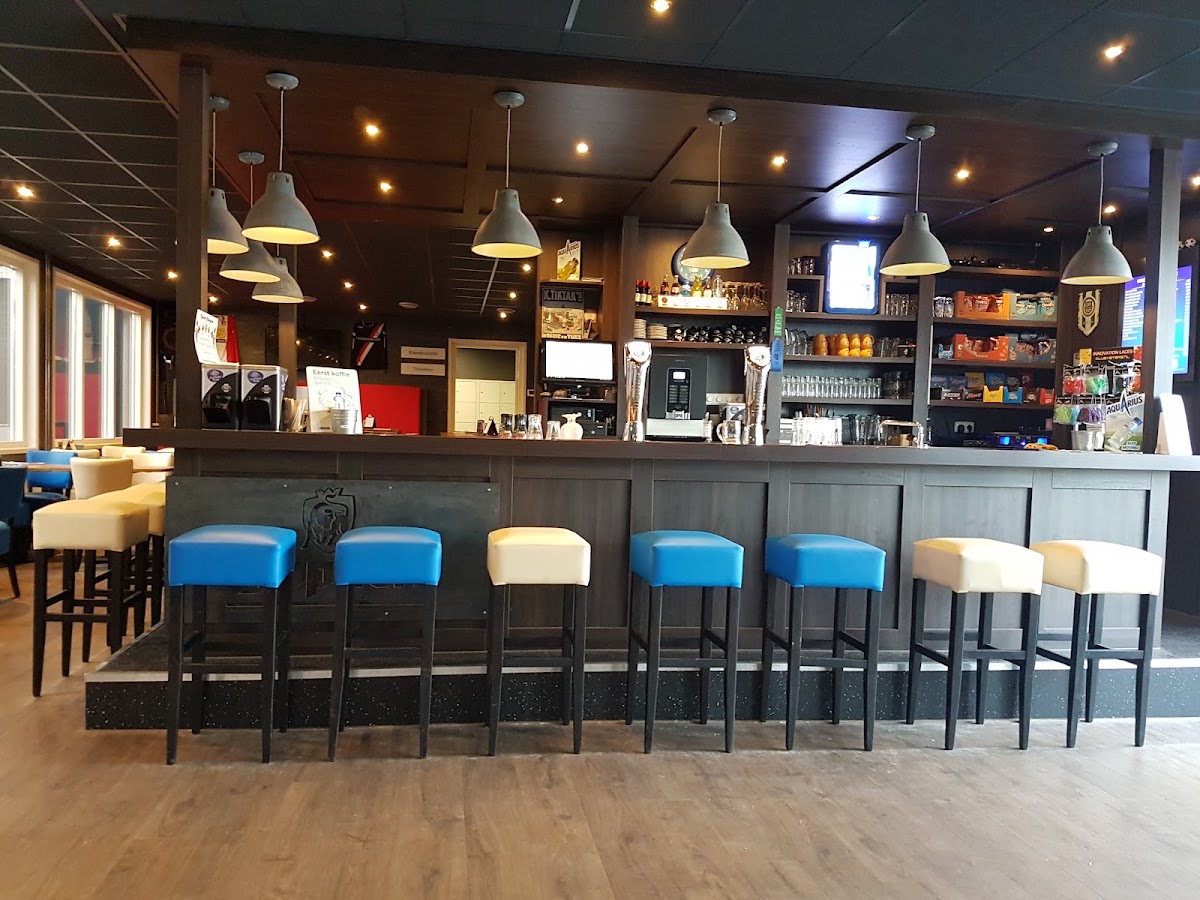 Modern padelbaan clubhuis met bar, blauwe barstoelen en houten vloer