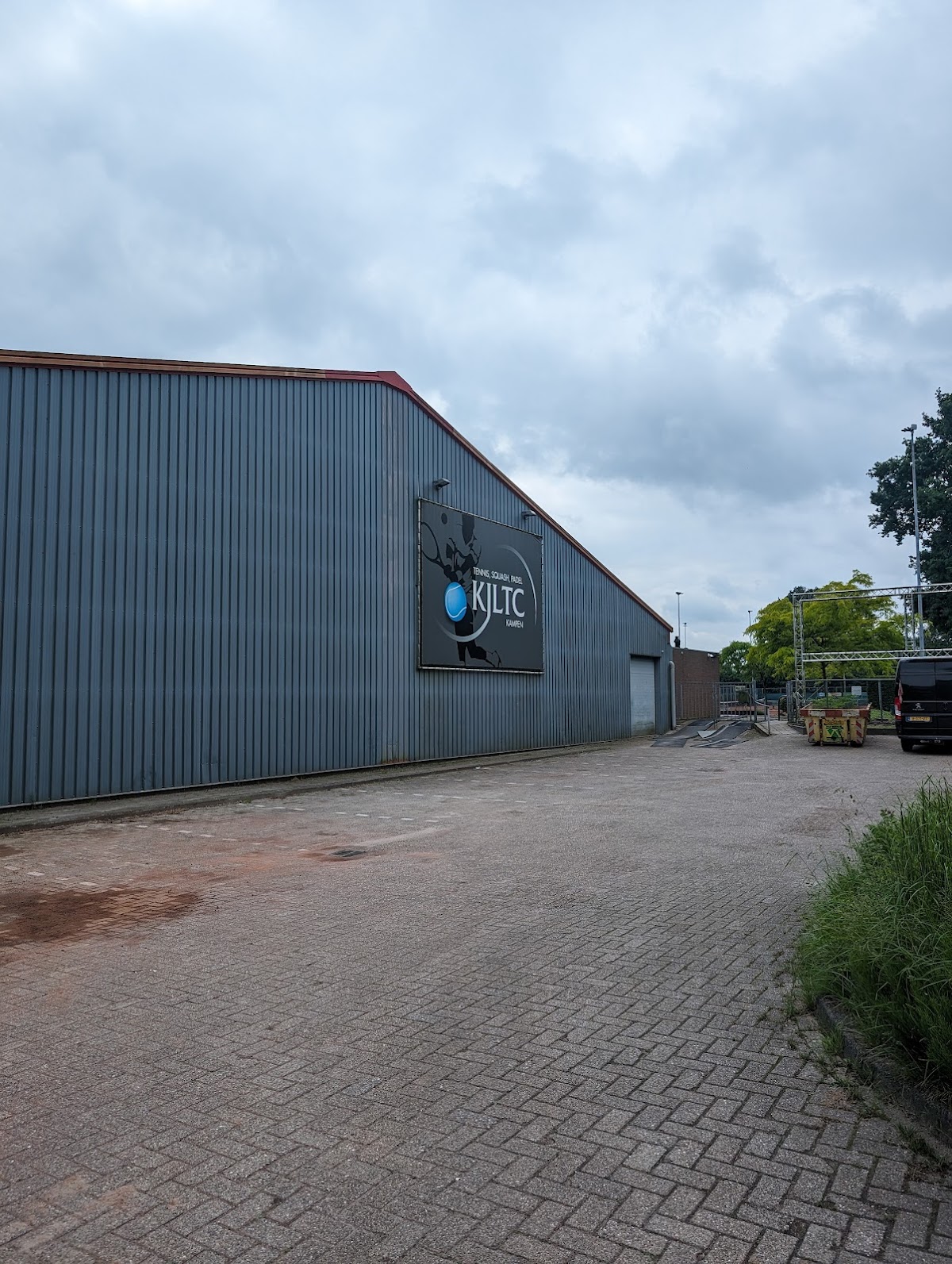 KILTC padel clubgebouw met golfplaten gevel en parkeerterrein