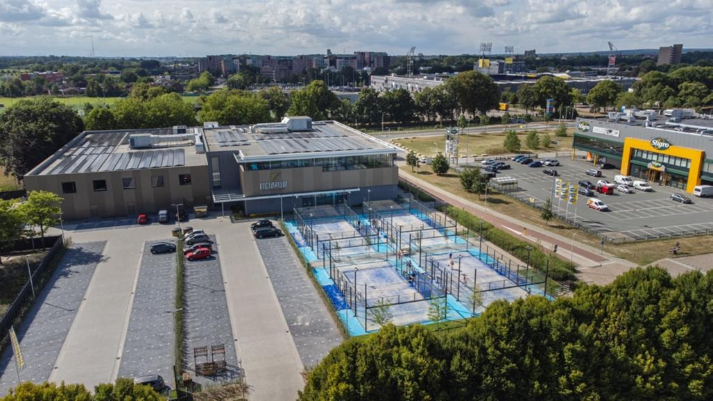 Luchtfoto padel club met blauwe courts, clubhuis en parkeerplaats in groen gebied
