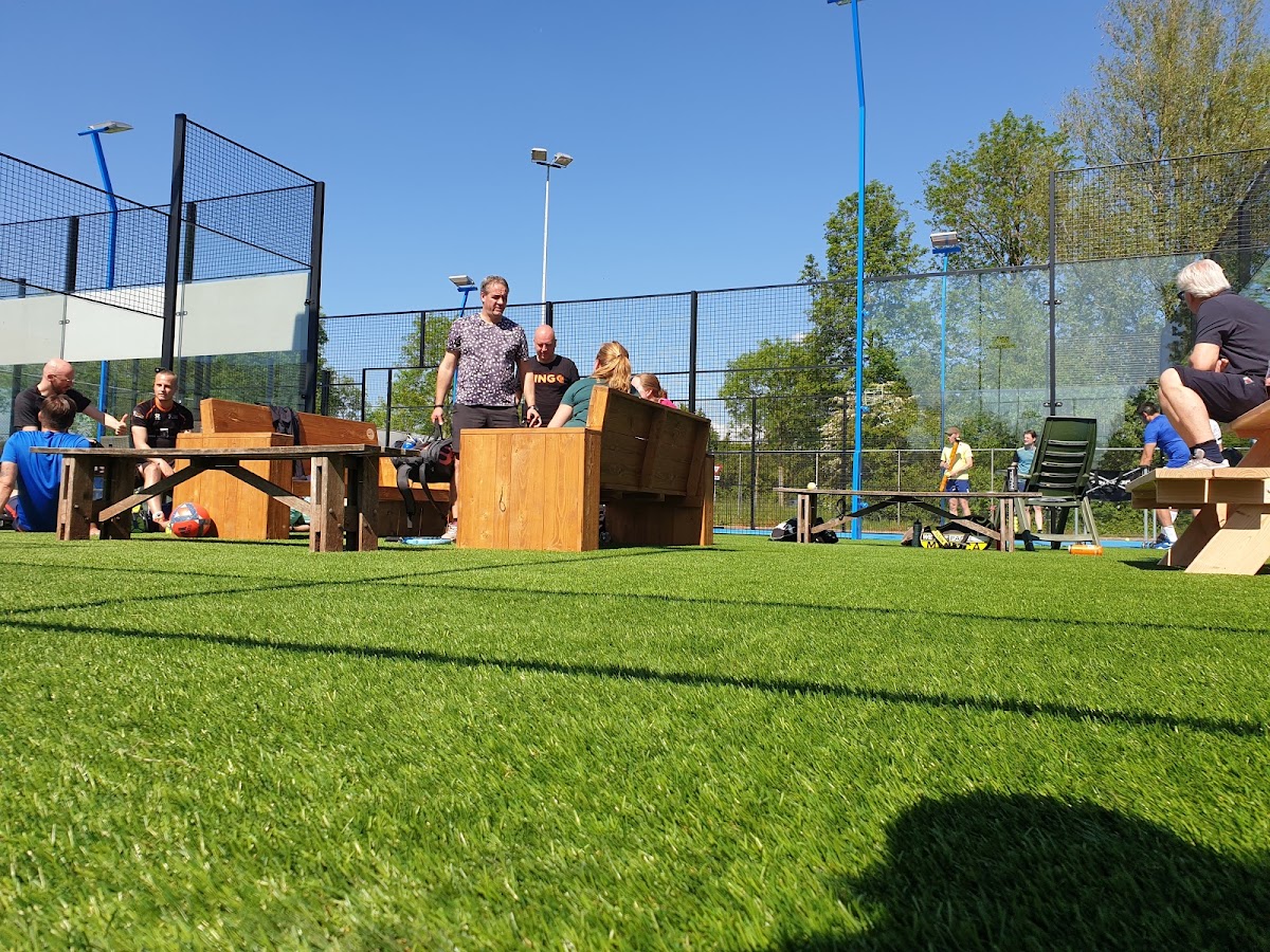 Outdoor padelclub met kunstgrasveld, houten constructies en toeschouwers op zonnige dag
