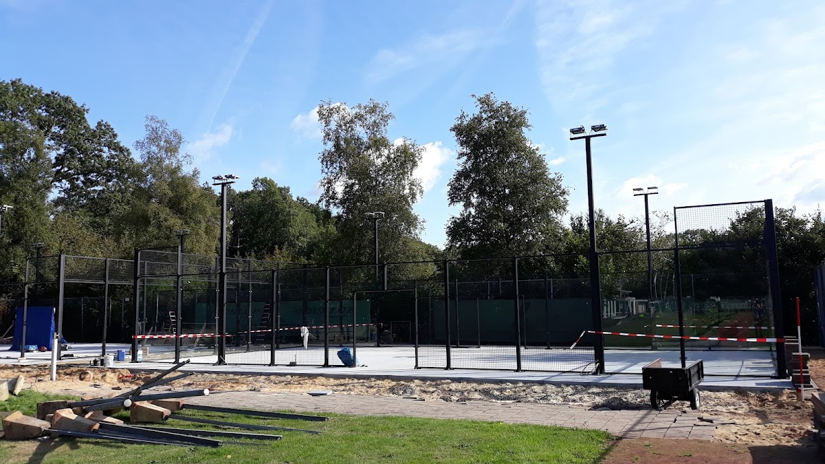 Outdoor padelclub met meerdere banen, floodlights en groene omgeving onder blauwe hemel