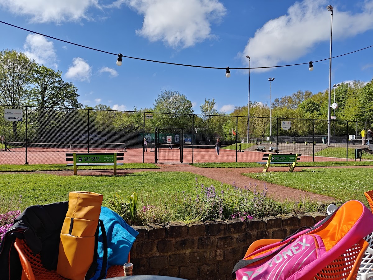 Outdoor padelclub met groene velden, bloemen en verlichte courts op zonnige dag