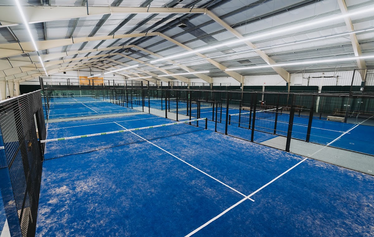 Binnenpadelclub met blauwe hardcourtbanen, netten en moderne LED-verlichting