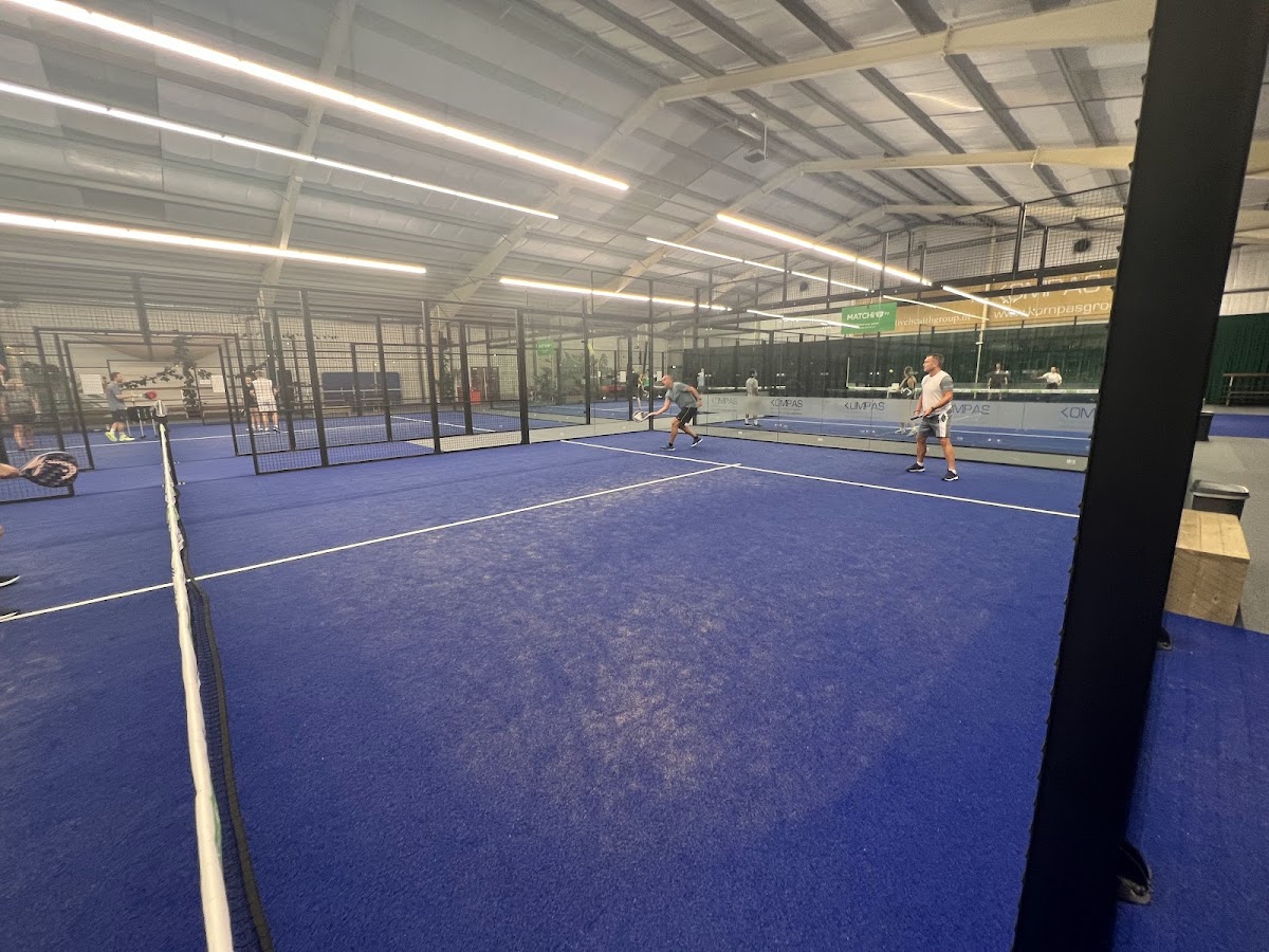 Binnenpadelclub met blauwe hardcourtbanen en fluorescerende verlichting