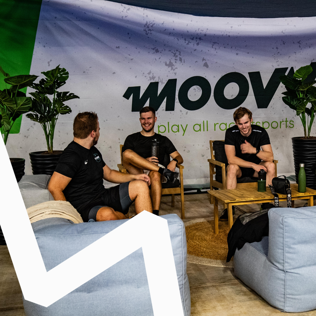MOOV padel club lounge met drie mannen in zwarte shirts zittend op houten stoelen