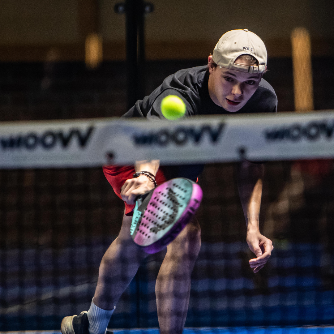 Jonge padel speler in actie op indoor court met blauwe QuickPadel ondergrond