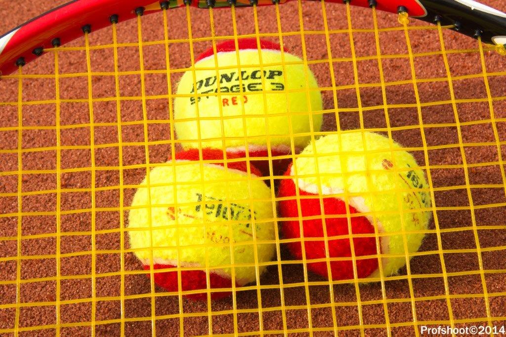 Gele padelballen op rood racket met geel netwerk op bruine ondergrond