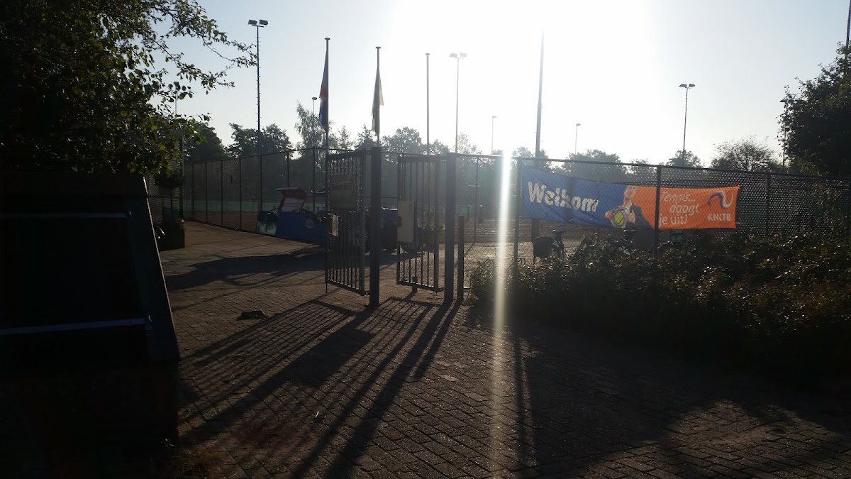 Buitenpadelclub met verlichting en welkomsbord bij zonsondergang
