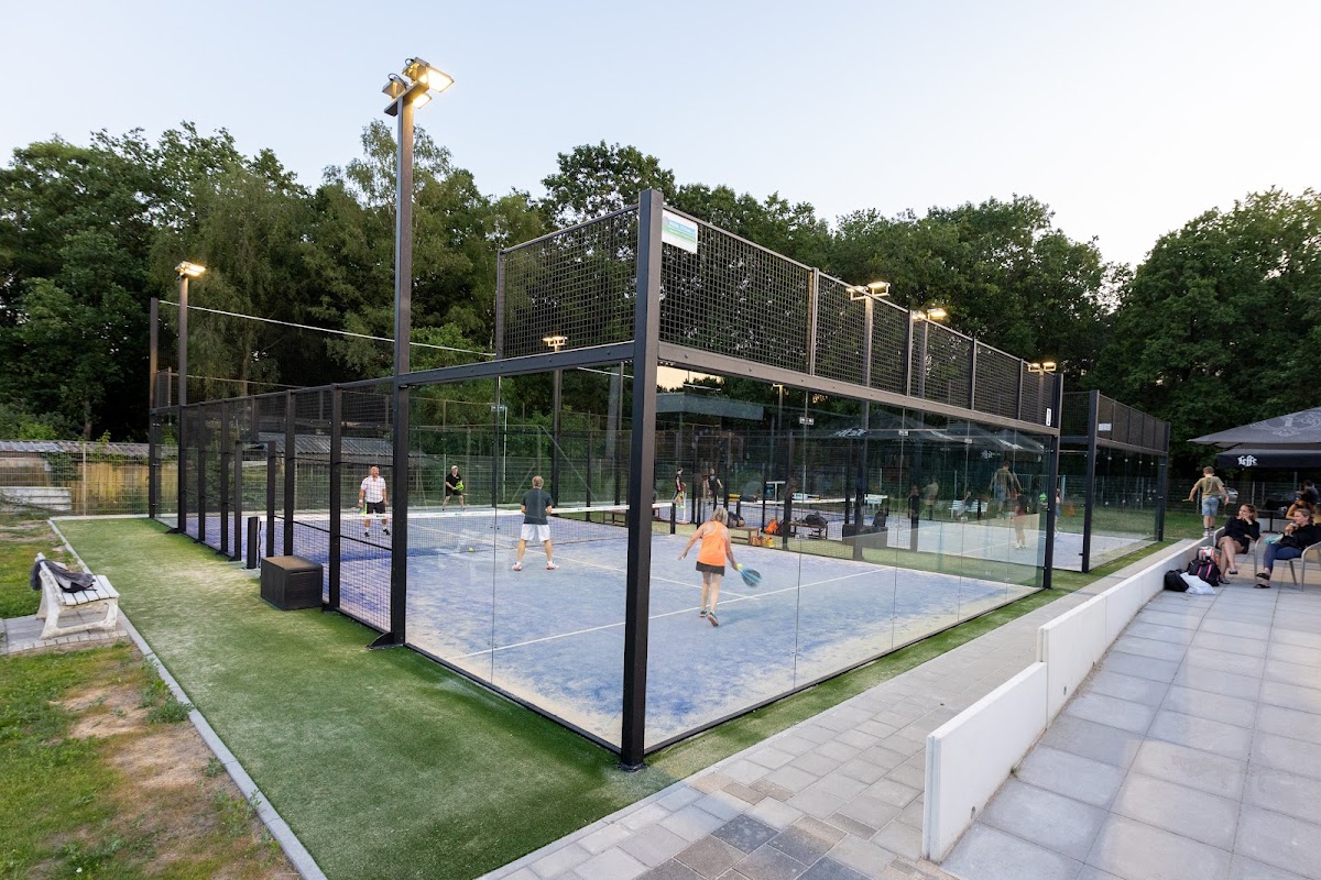 Moderne outdoor padelclub met verlichte courts, glas afscheidingen en zitgedeelte