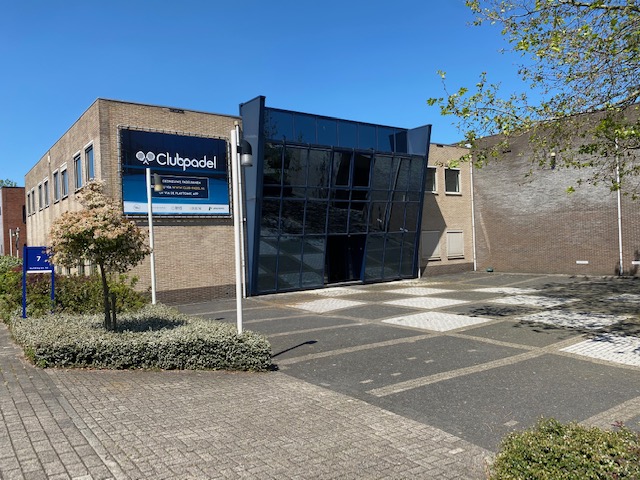 Clubpadel padelclub ingang met donkere glazen voorgevel en bakstenen zijgevels.